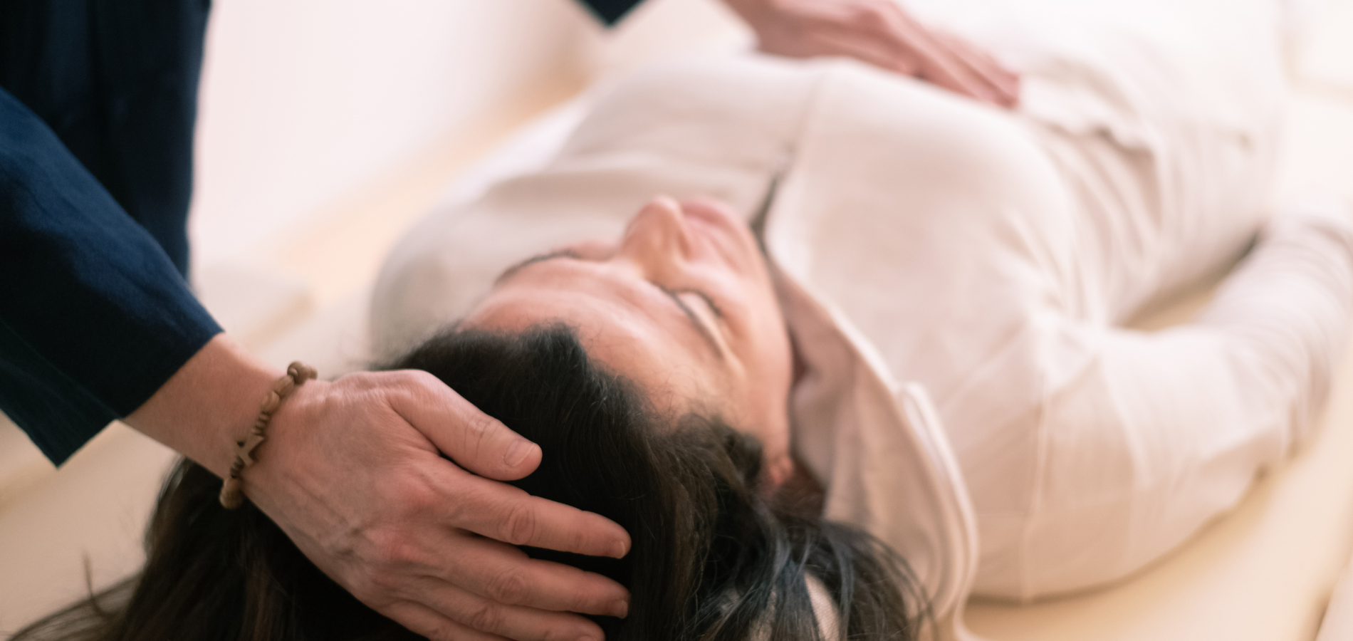 reiki practitioner placing hands gently near a client's head during a session